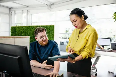 A woman demonstrating something on a computer to a man