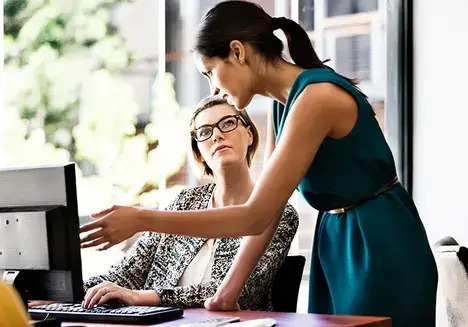 A woman showing something on a computer to another woman